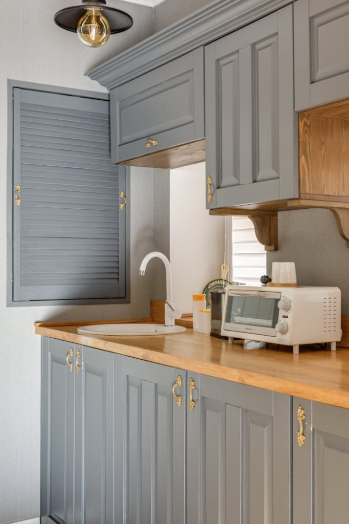 Stylish kitchen with grey cabinets and wooden countertops featuring modern appliances.